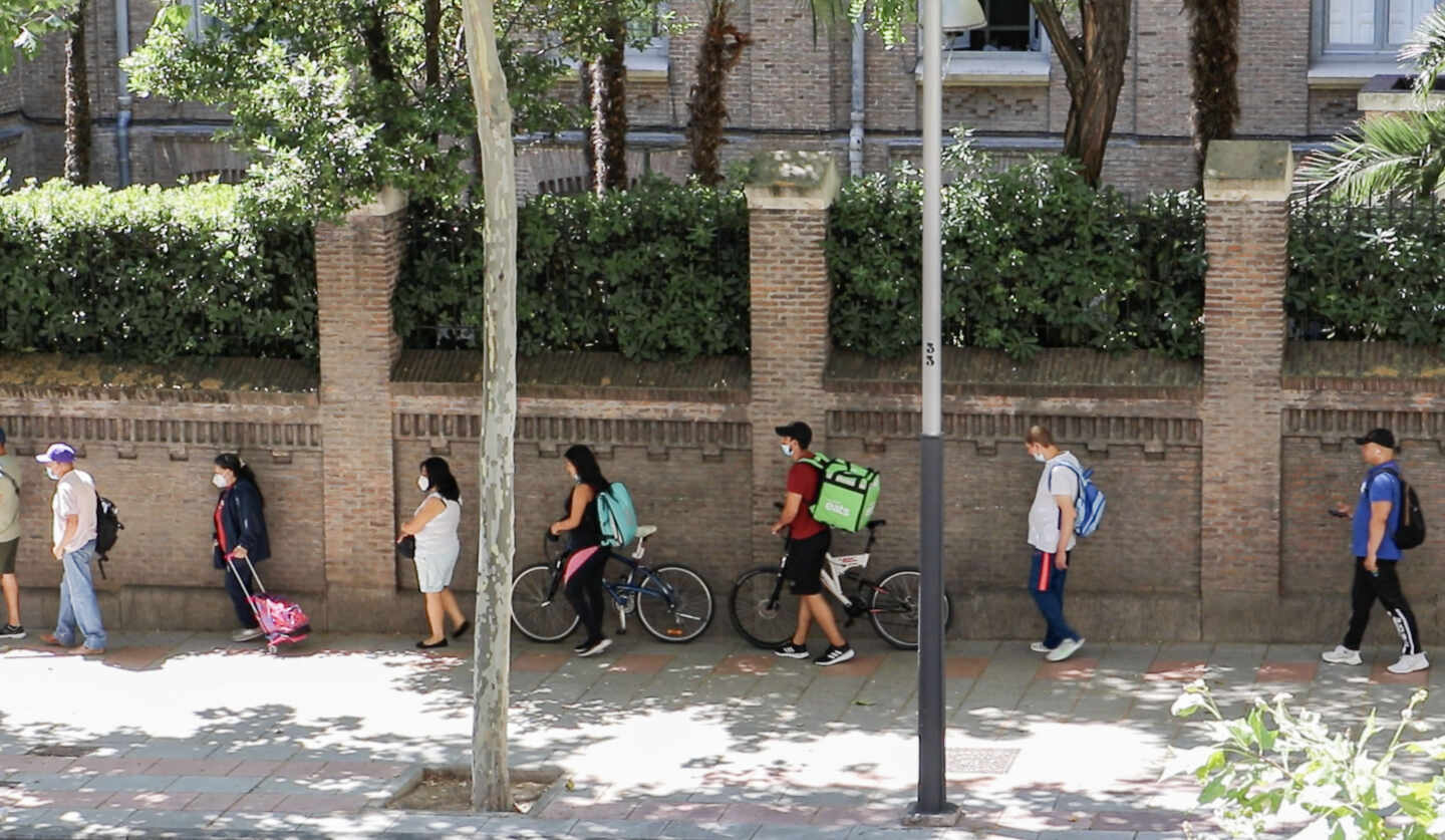 Dos riders hacen cola en Martínez Campos para conseguir una bolsa de comida