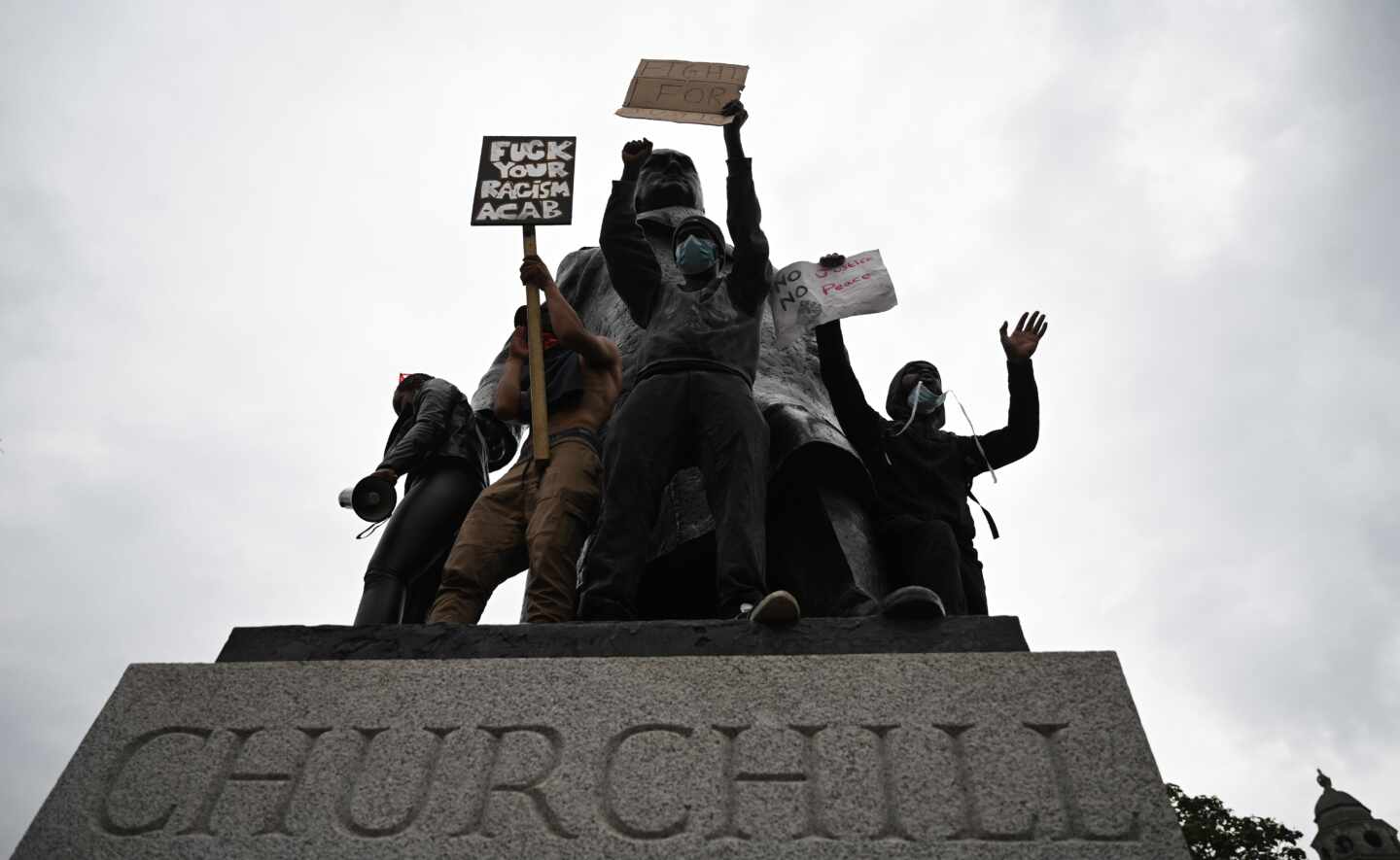 Un grupo de manifestantes se encarama en la estatua de Churchill con carteles en los que se le tilda de "racista". 