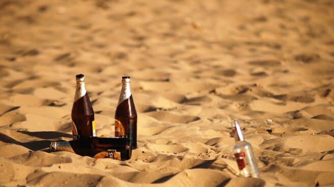 Botellas de alcohol en la arena de una playa.