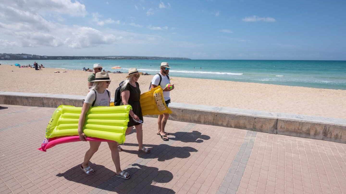 Turistas caminan por el paseo de la playa en Palma de Mallorca.