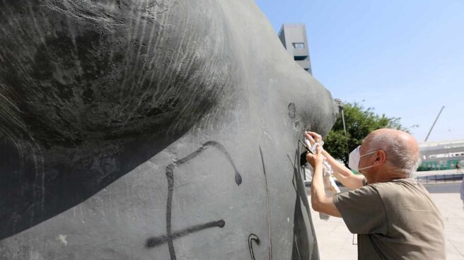 El artista Antonio López eliminando las pintadas que han vandalizado su obra 'La Mujer de Coslada'.