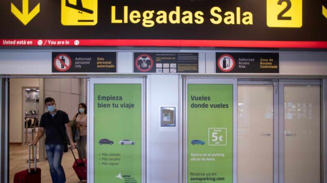 Pasajeros con mascarillas llegan al aeropuerto de Madrid-Barajas.