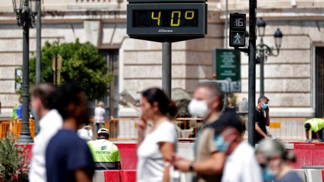 Varias personas pasan ante un termómetro urbano de la Comunidad Valenciana que marca una temperatura de 40º.