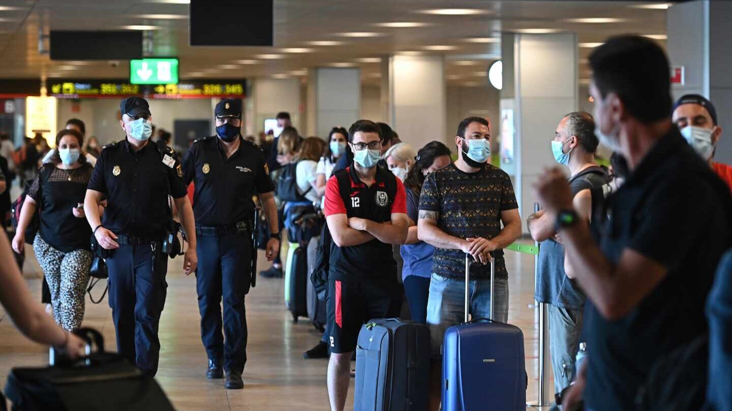 Policías en la T-1 del aeropuerto de Barajas junto a una hilera de pasajeros.
