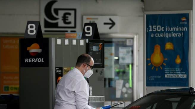 Un conductor reposta con mascarilla en una gasolinera.