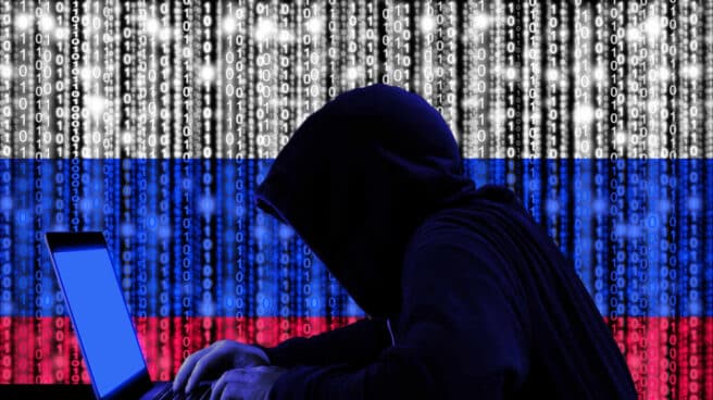 Un hacker delante de una bandera de Rusia formada por un código binario.