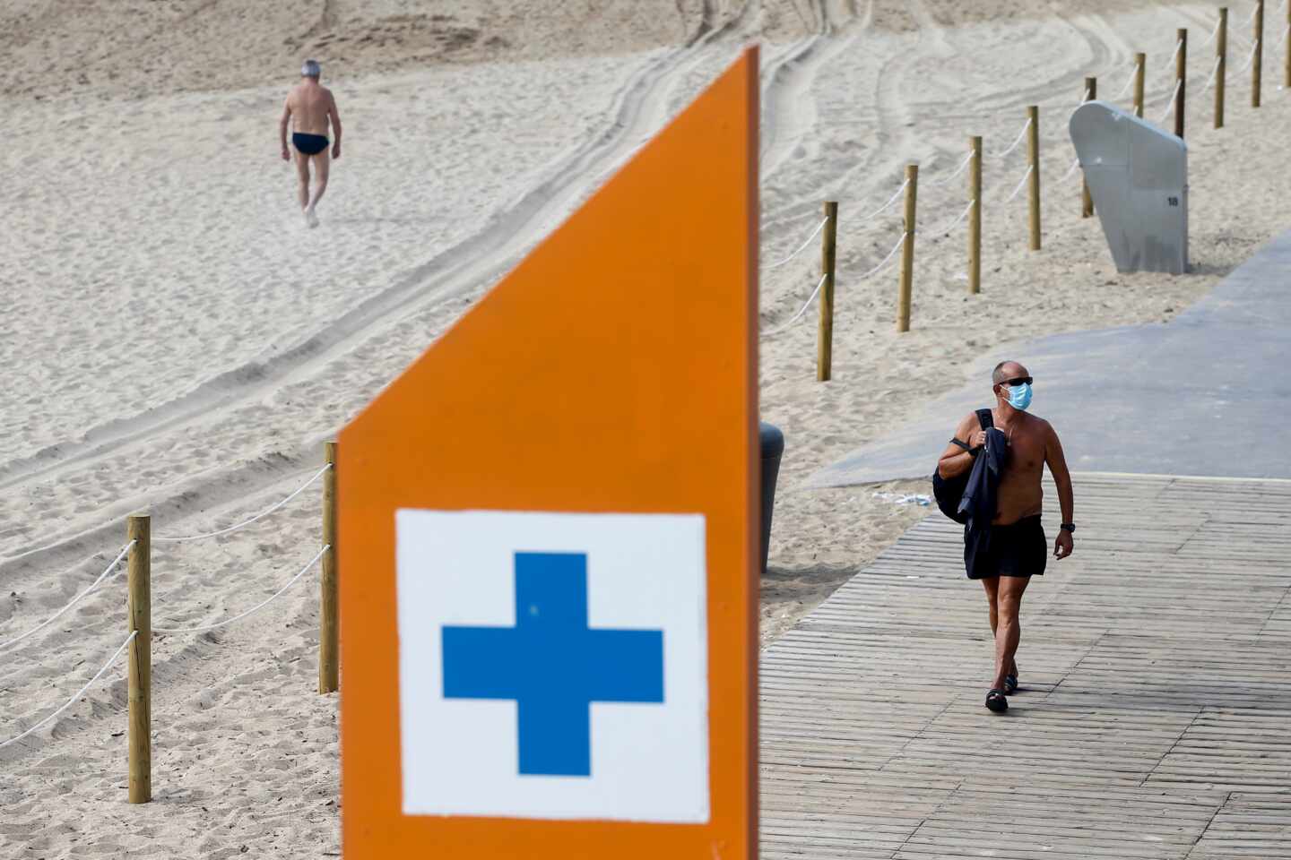 Un bañista con mascarilla en la playa de la Barcelona, en Barcelona.