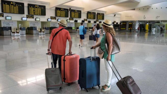 Varios turistas comprueban sus vuelos en un aeropuerto español