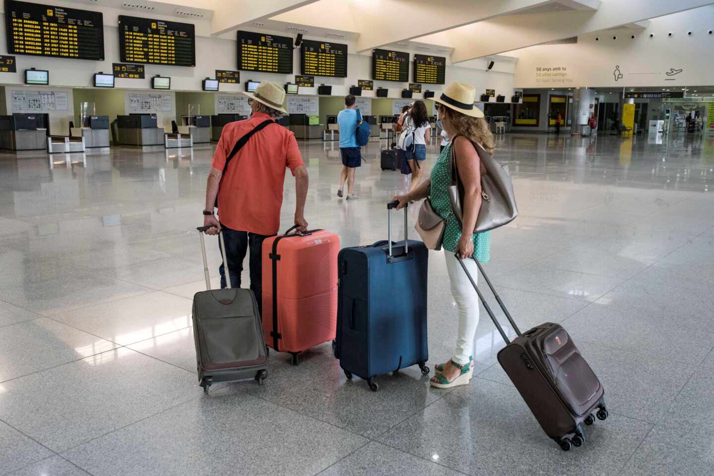 Varios turistas comprueban sus vuelos en un aeropuerto español