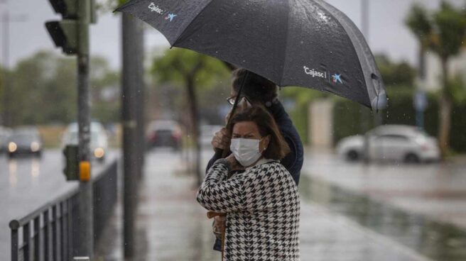 Dos personas sujetan un paraguas durante una tormenta. Dos personas sujetan un paraguas durante una tormenta.