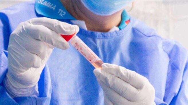 Un trabajador sanitario protegido sostiene una de las probetas utilizadas para la realización de tests PCR.