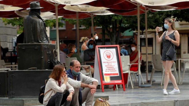 Una pareja de turistas fuman sentados en una plaza del centro de Oviedo.