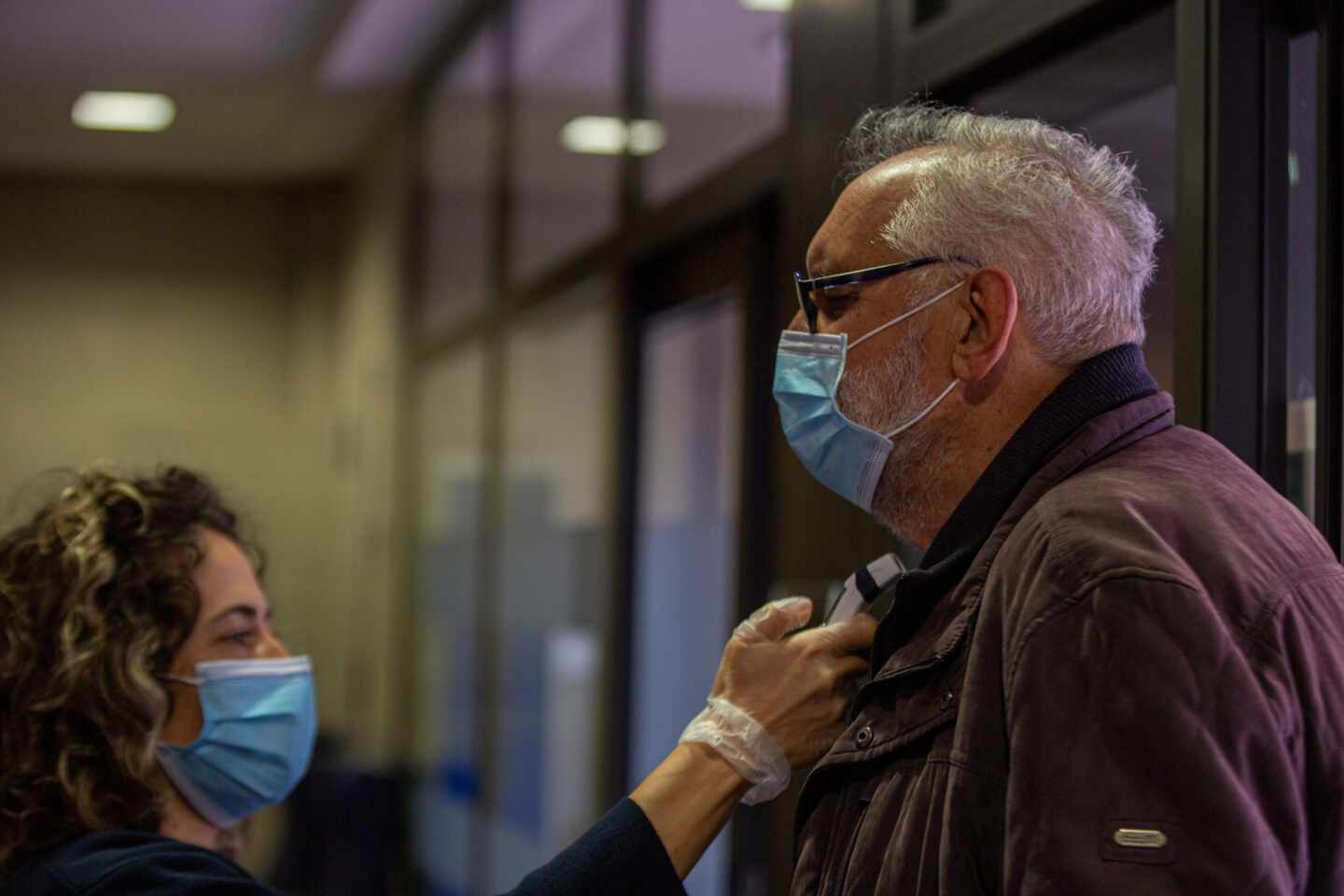 , una empleada de una residencia de Vitoria toma la temperatura a un hombre que va a visitar a su familiar