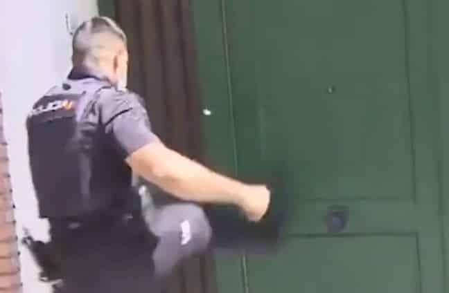 Un policía trata de forzar a patadas la puerta de una vivienda ocupada.