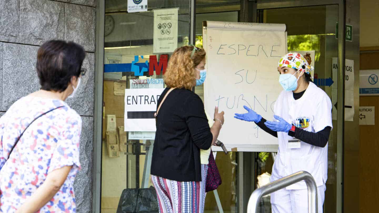 Una trabajadora del centro de salud de Doctor Cirajas atiende a una señora en la puerta