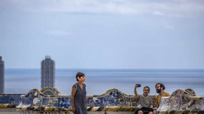 Una mujer camina junto a una pareja tomando un selfie en el Parque Güell.