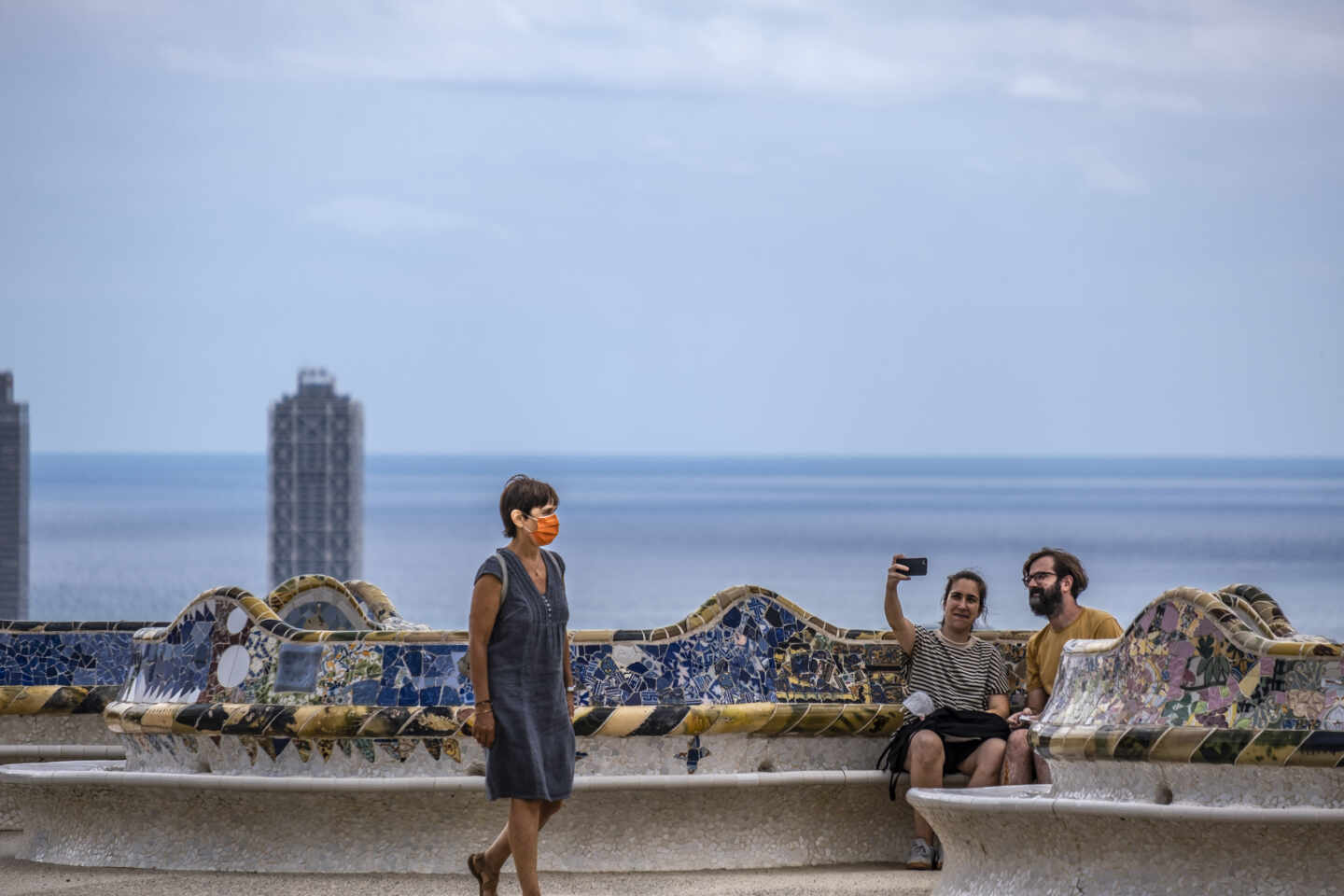 Una mujer camina junto a una pareja tomando un selfie en el Parque Güell.