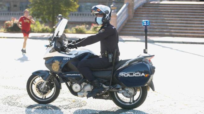 Un policía, de patrulla en motocicleta por la Plaza de España de Sevilla.