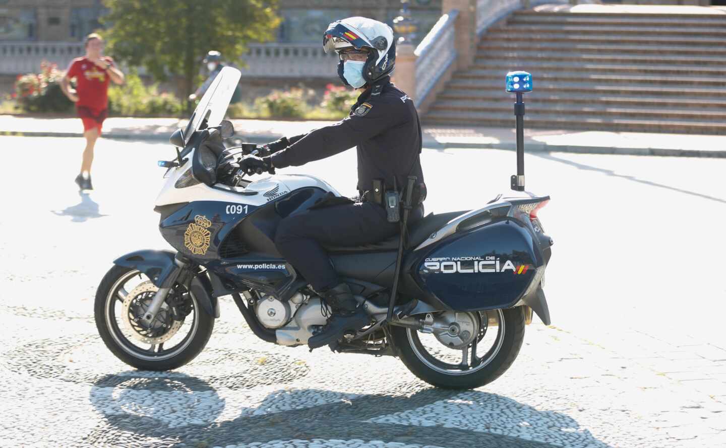 Un policía, de patrulla en motocicleta por la Plaza de España de Sevilla.