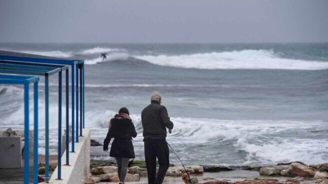 Dos personas caminan a la orilla de la costa de Biniancolla, en la isla de Menorca.