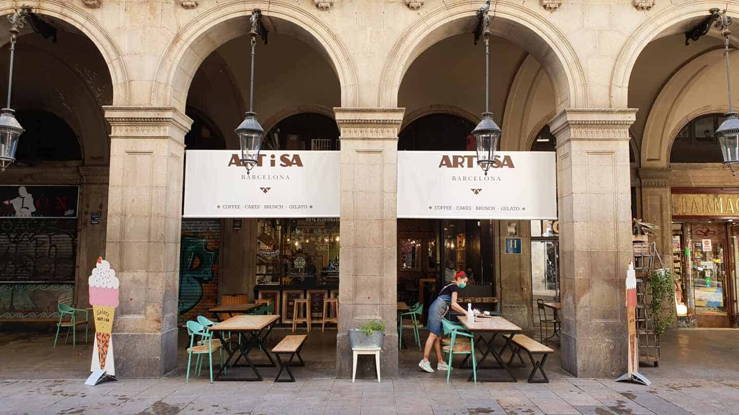 una mujer recoge la mesa de un restaurante en Barcelona