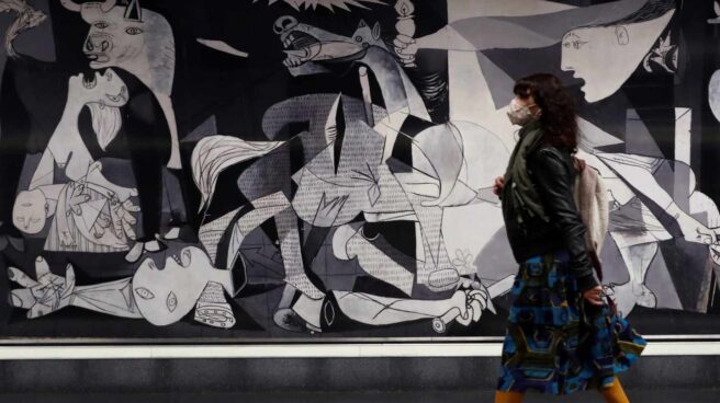 Una mujer pasa ante una reproducción del Guernica de Picasso ubicado en Atocha.