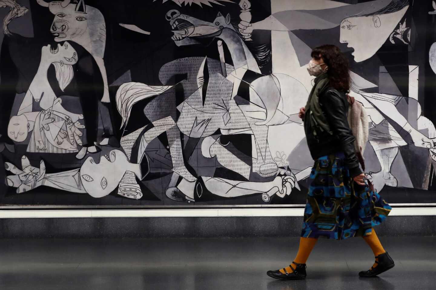 Una mujer pasa ante una reproducción del Guernica de Picasso ubicado en Atocha.