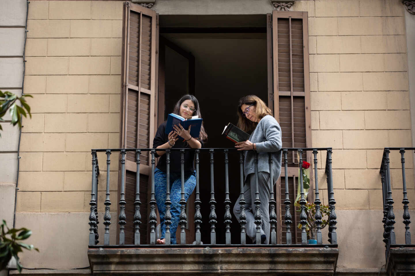 Dos jóvenes leen en el balcón de su casa