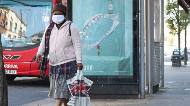 Una mujer con mascarilla camina por una calle de Londres.