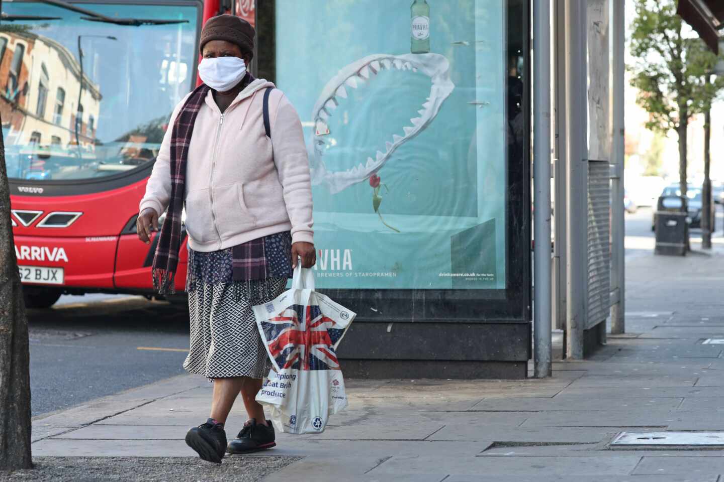 Una mujer con mascarilla camina por una calle de Londres.