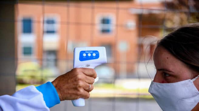 Un sanitario toma la temperatura a una mujer en la Zona Básica de Salud.