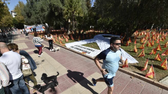 Varias personas pasean junto a las banderas de España en el Parque Isidoro Medina, en Murcia.