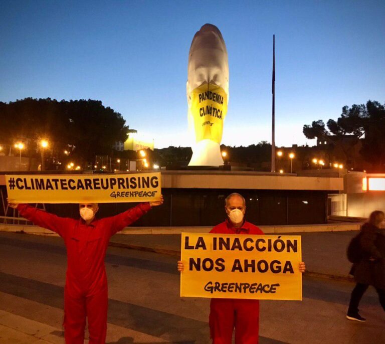 Greenpeace coloca una mascarilla gigante en una estatua de la plaza de Colón