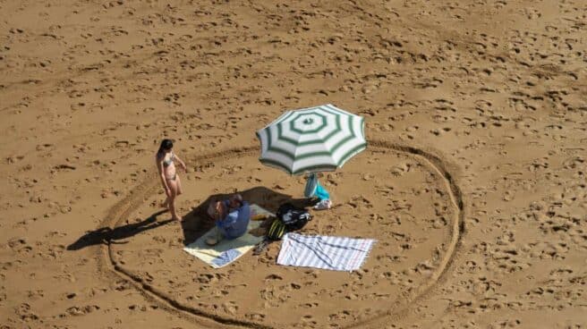 Un bañista marca la distancia de seguridad en la playa de Gijón.