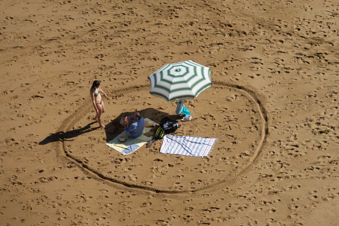 Un bañista marca la distancia de seguridad en la playa de Gijón.