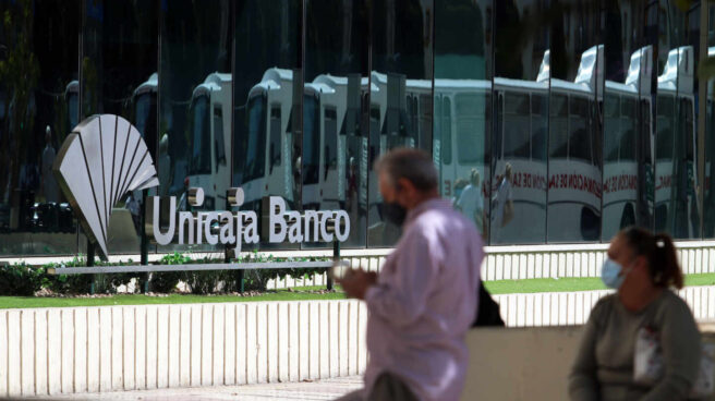 Dos personas en las inmediaciones de la sede de Unicaja Banco en Málaga.
