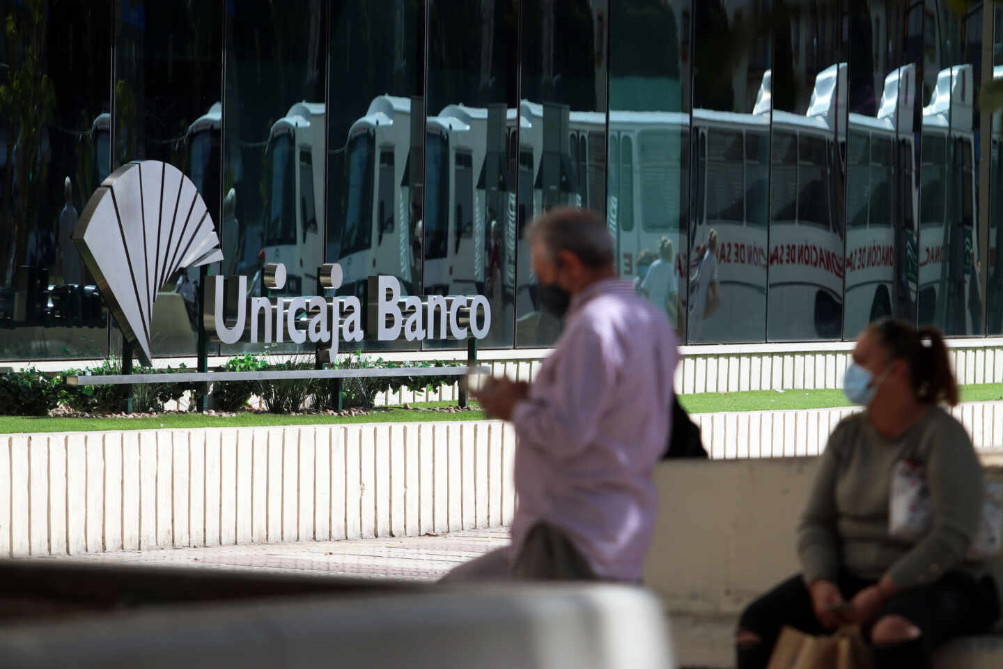 Dos personas en las inmediaciones de la sede de Unicaja Banco en Málaga.