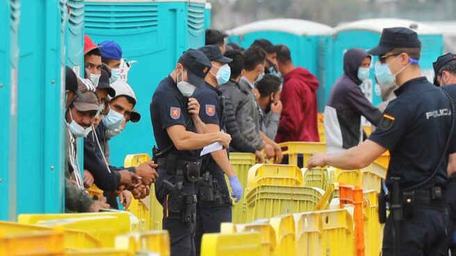 Policías nacionales y migrantes, en el muelle grancanario de Arguineguín.
