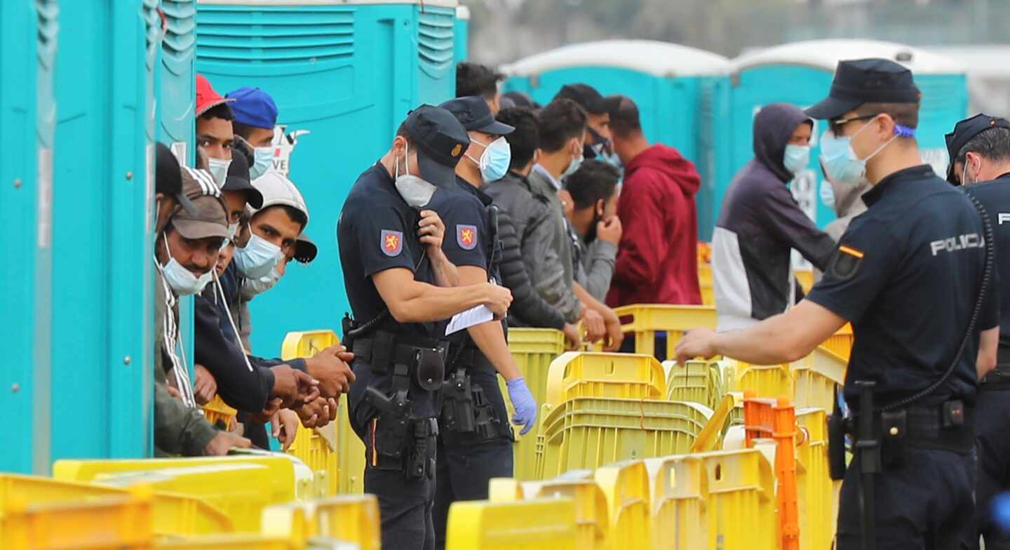 Policías nacionales y migrantes, en el muelle grancanario de Arguineguín.