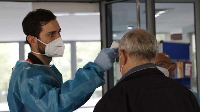 Personal sanitario toma la temperatura a una persona en la entrada de un centro de mayores en Madrid.