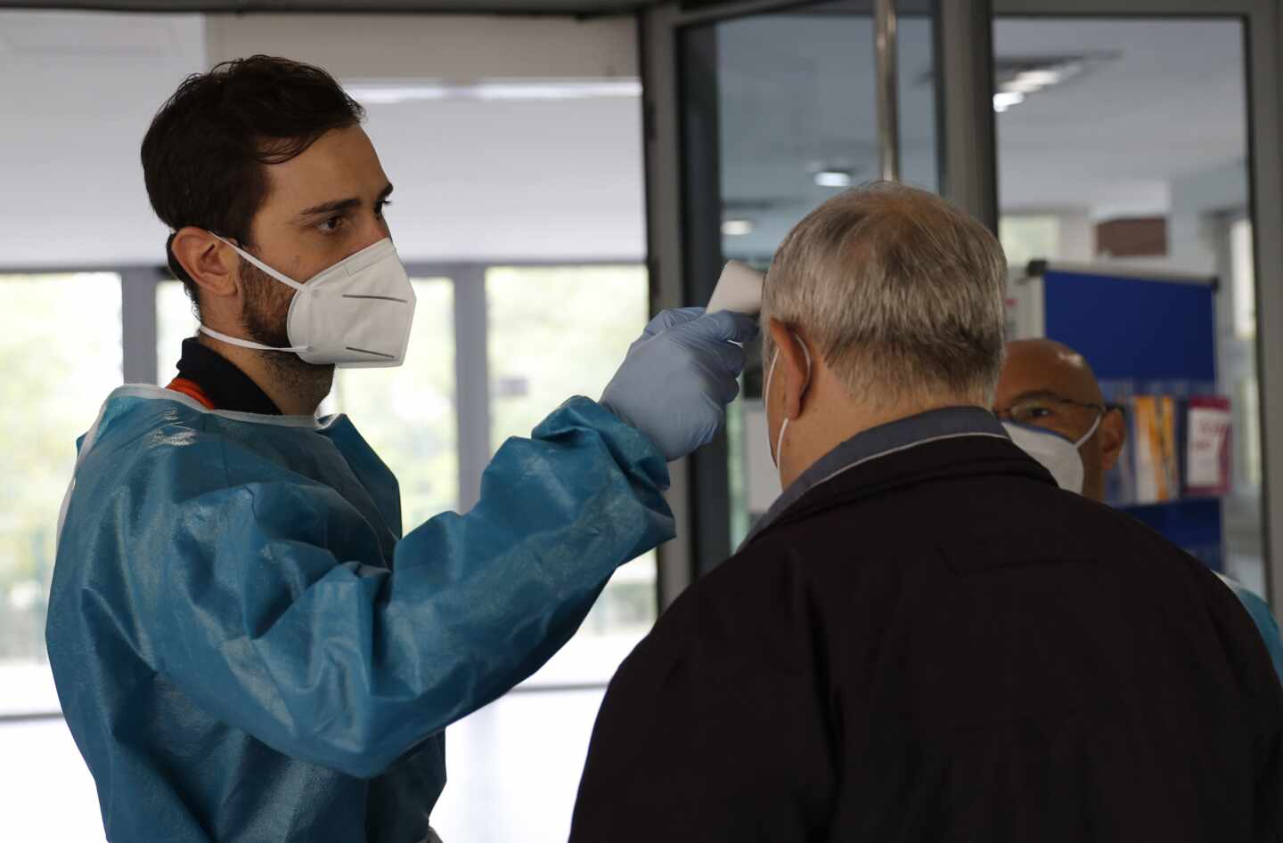 Personal sanitario toma la temperatura a una persona en la entrada de un centro de mayores en Madrid.