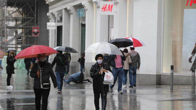 Transeúntes caminan por el centro de la capital protegiéndose de la lluvia.