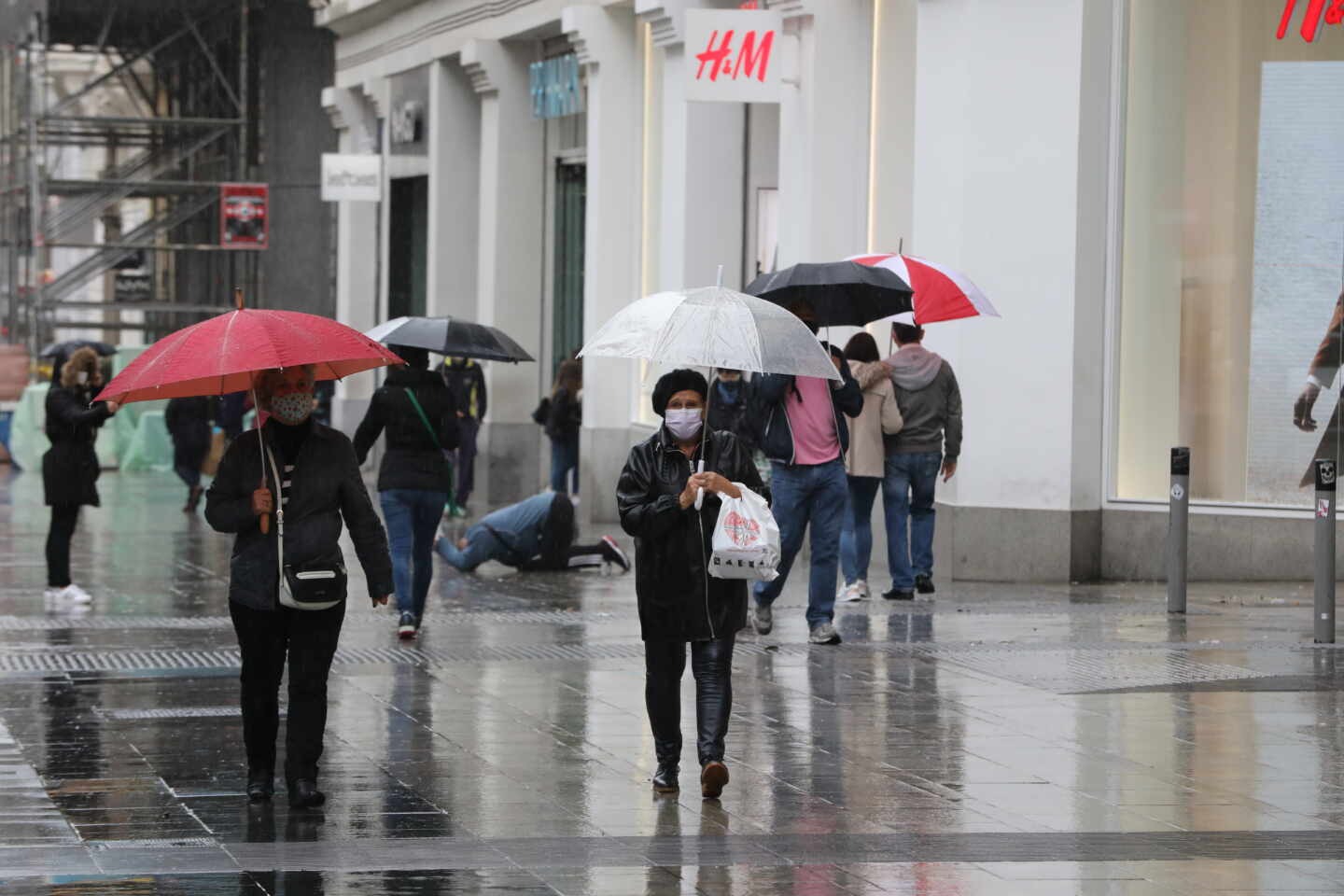 Transeúntes caminan por el centro de la capital protegiéndose de la lluvia.