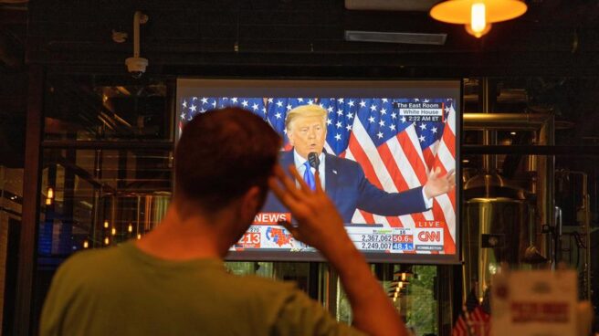 Un hombre ve por televisión al presidente Donald Trump durante la noche electoral.