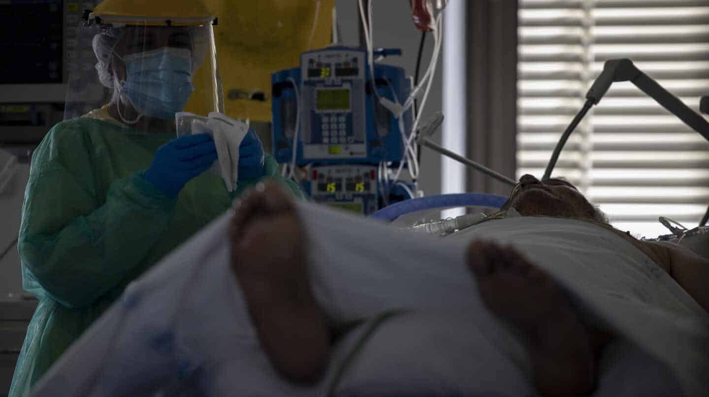 Un sanitario atiende a un paciente en la UCI del Hospital Ramón y Cajal, en Madrid.