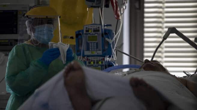 Un sanitario atiende a un paciente en la UCI del Hospital Ramón y Cajal, en Madrid.