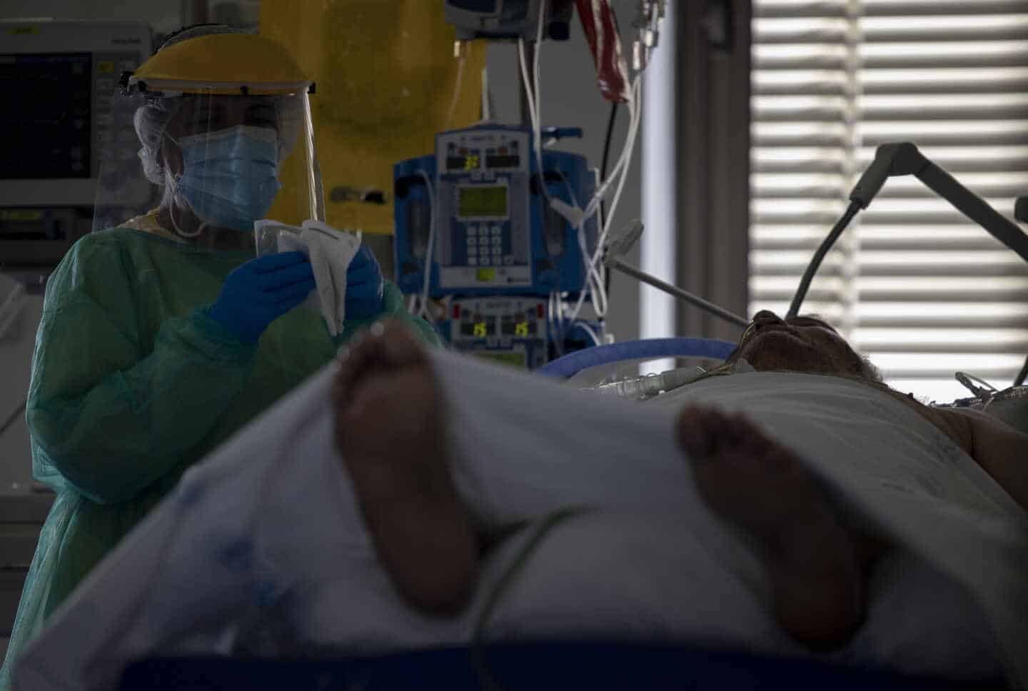 Un sanitario atiende a un paciente en la UCI del Hospital Ramón y Cajal, en Madrid.