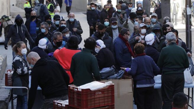 Decenas de personas hacen cola para recibir ayuda en un centro social religioso de Barcelona.