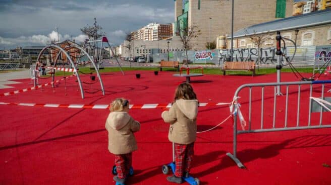 Dos niñas observan un parque cerrado de Santander.