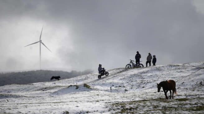 Varias personas transitan por un paraje nevado en la localidad cántabra de Requejo, en un fin de semana marcado por las bajas temperaturas en el norte peninsular.